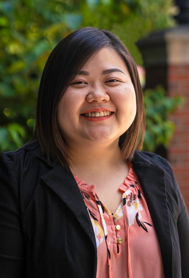 Asian woman smiling in front of trees