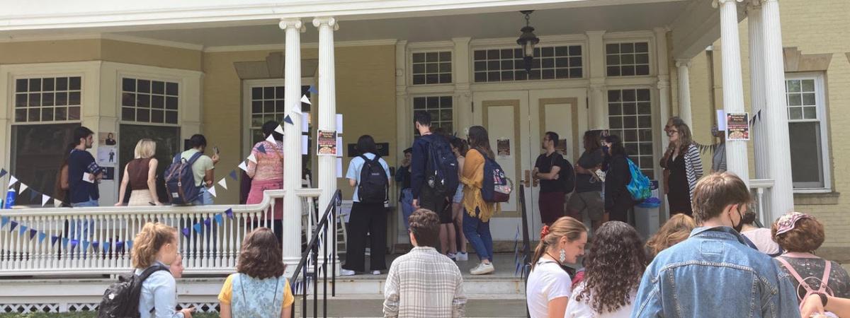 group of graduate students outside of yellow building with porch