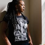 Laina Dawes wearing a black, heavy metal t-shirt and she's gazing out a window