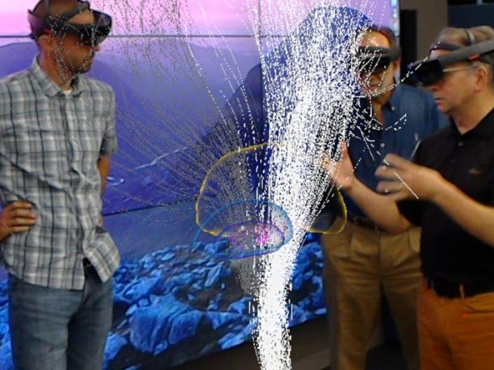 Men and women work with a hologram projection.