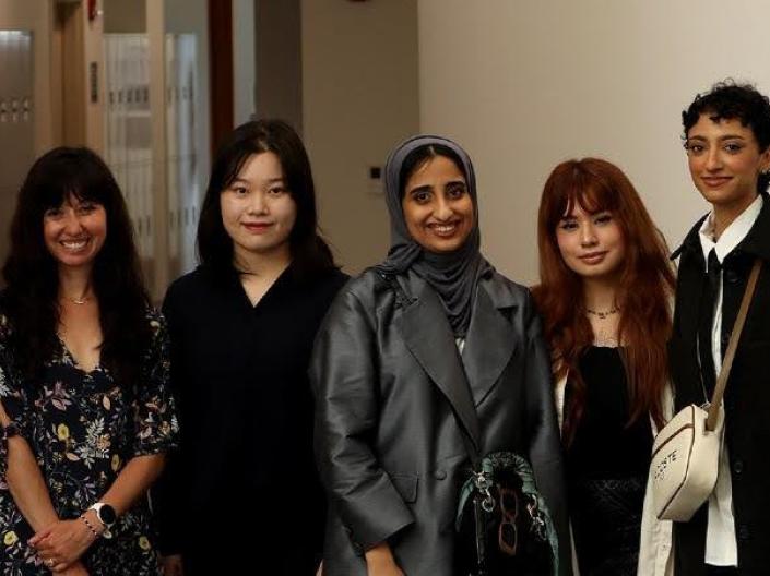 Eight individuals pose together in a hallway for a photo.