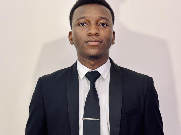 portrait image of Vinlaw Mudhwe wearing a black suit with black tie