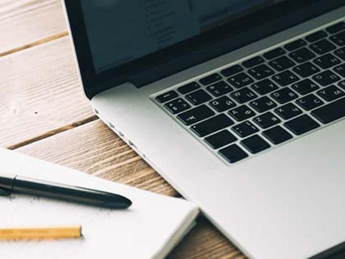 Computer and pen and paper on desk