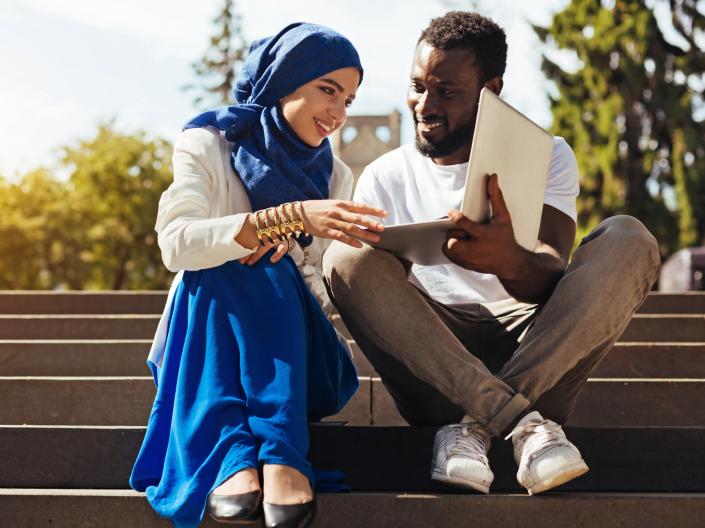 Two people sitting on stairs talking.