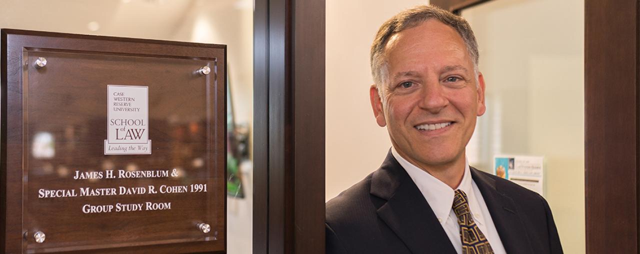 David Cohen in front of a plaque in the Law School