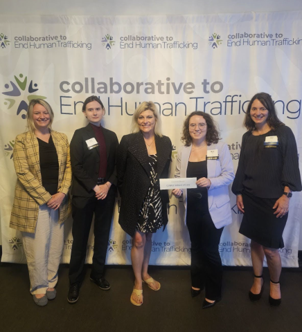 Five women standing in front of a banner that says "Collaborative to End Human Trafficking."