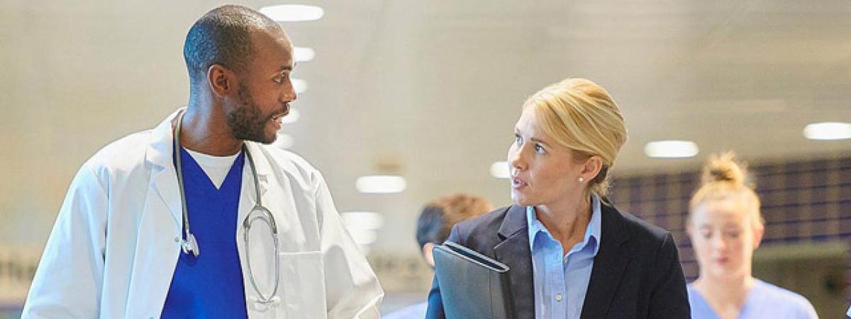 Picture of a male doctor and female colleague conversing in hallway