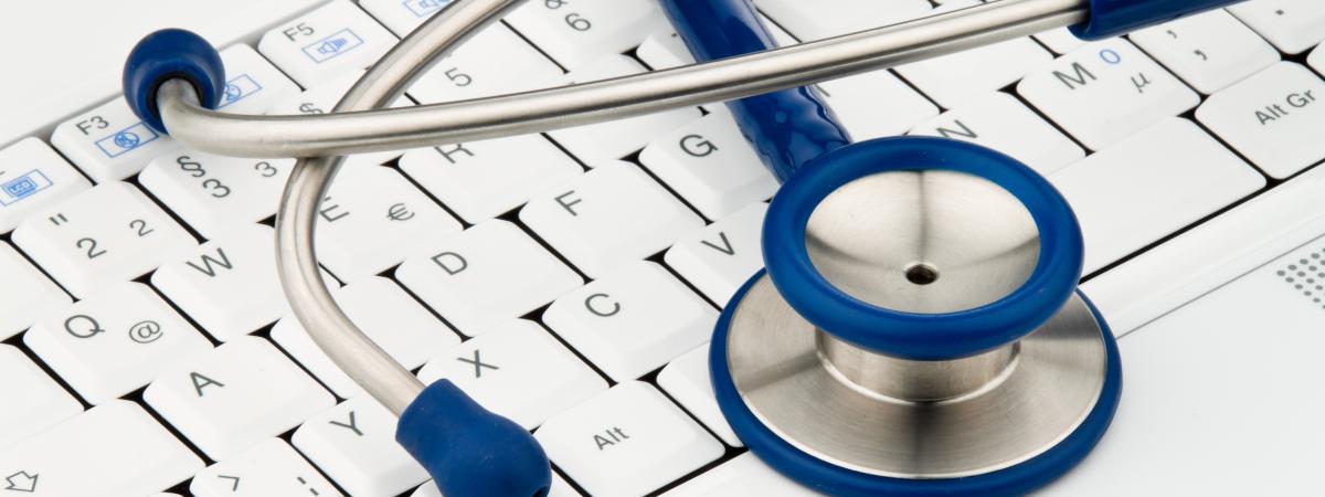 A stethoscope laying on top of a computer keyboard.