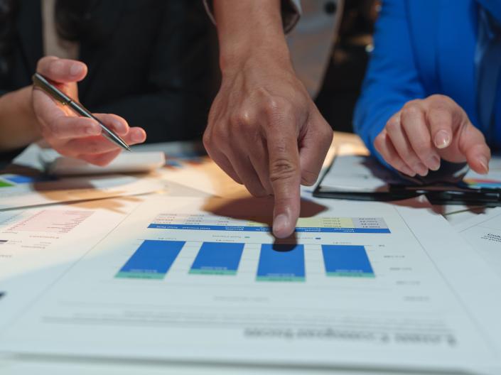 Three people at desk evaluating data.