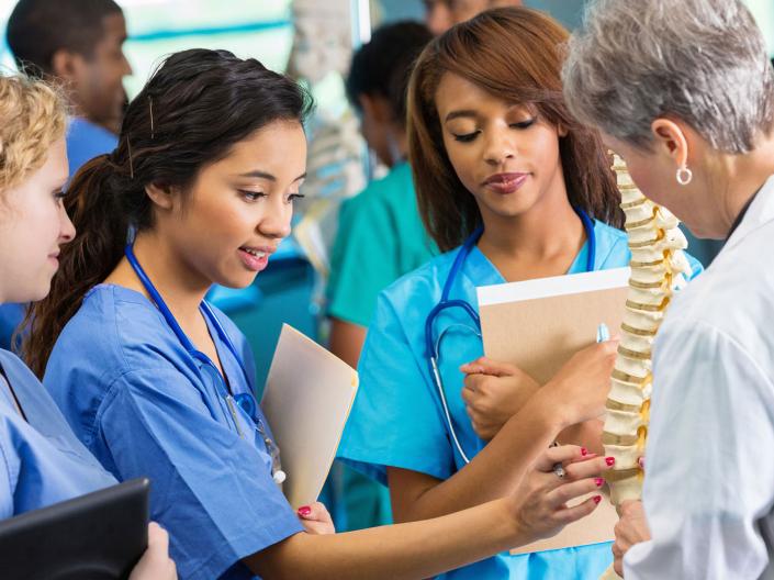 Medical students studying a model human skeleton 