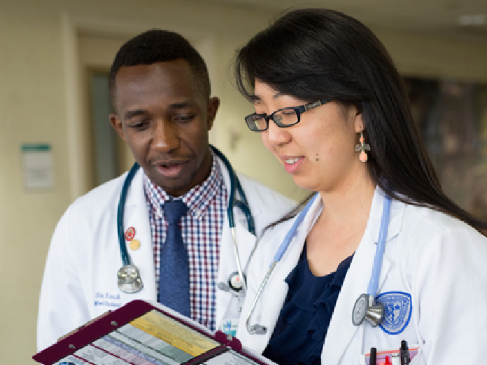 Two CWRU medical students in white coats in discussion on a clinical rotation