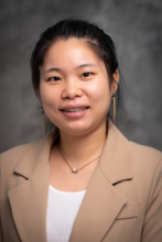 Woman with dark hair wearing a light suit jacket