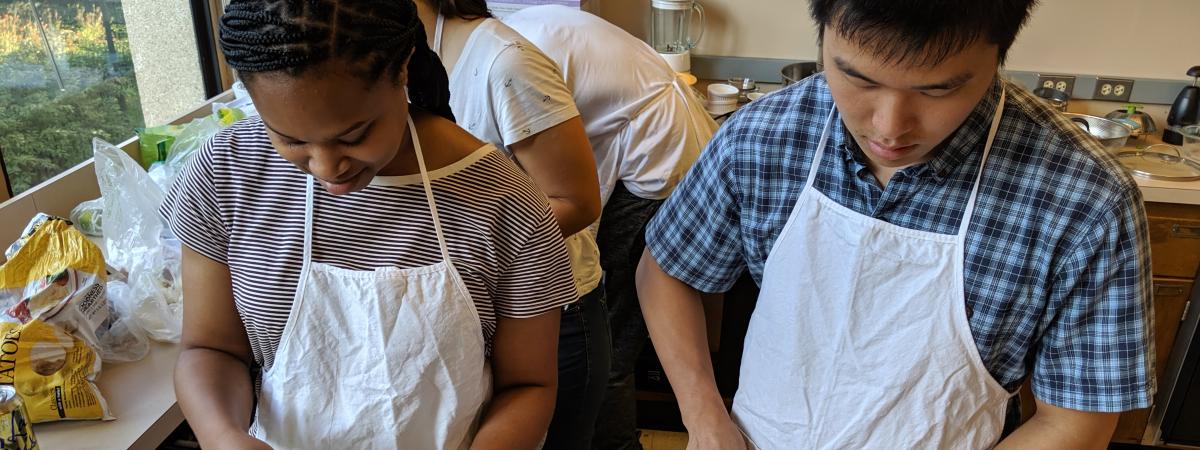 Two students in aprons slice ingredients for a frittata in the Department teaching kitchen.