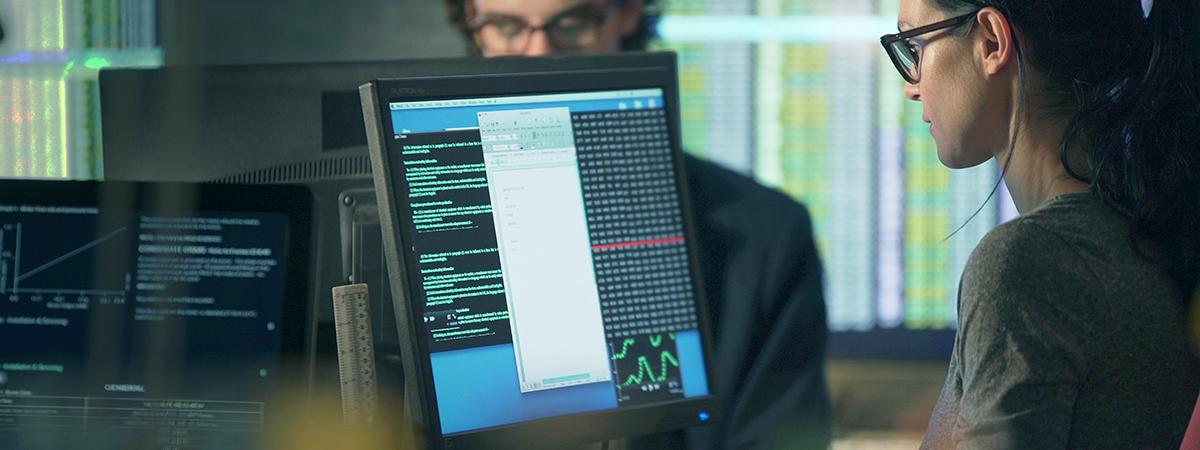 Two people working on computers analyzing data