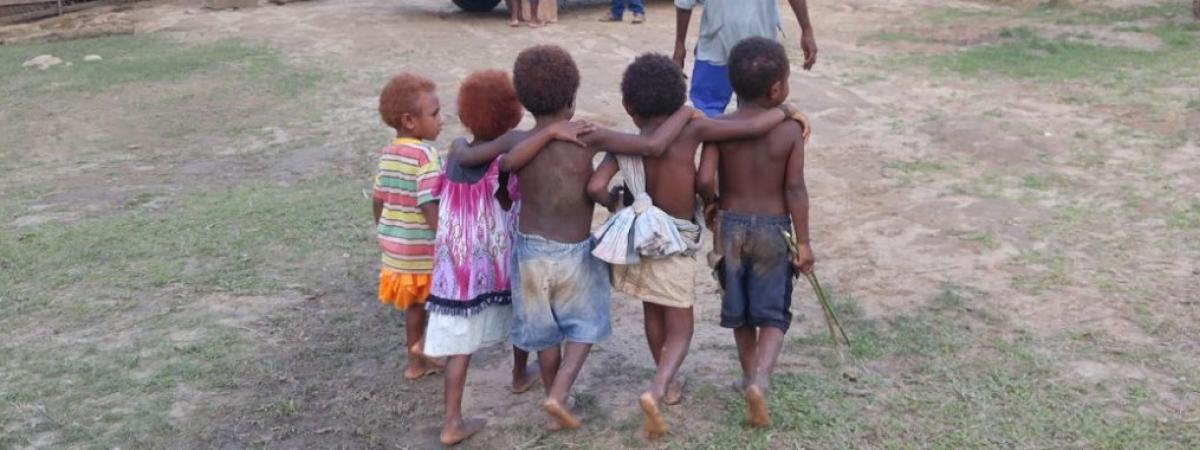 5 small barefoot children walking away in an outdoor setting in Papua New Guinea