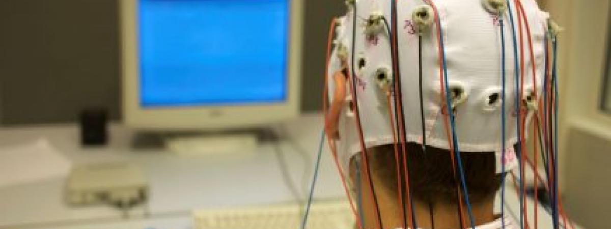 Man sitting in front of computer wearing skull cap measuring brain activity