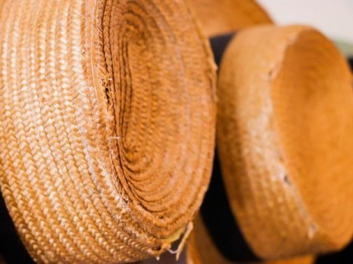 row of straw hats hanging on a wall