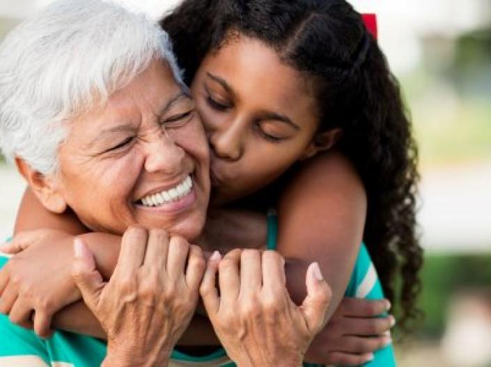 young girl hugging grandmother around her neck