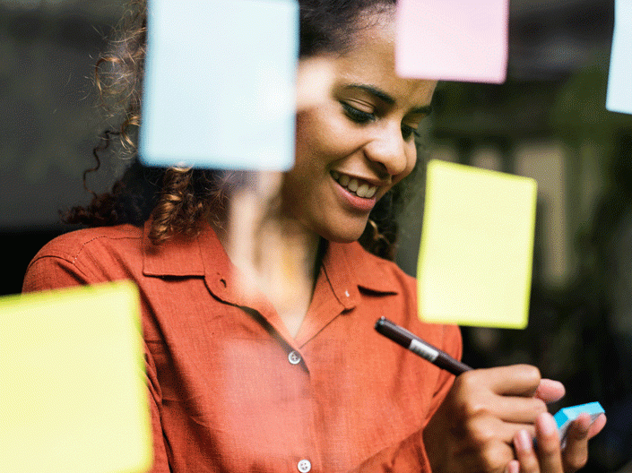 photo of a woman behind a glass wall writing notes on paper