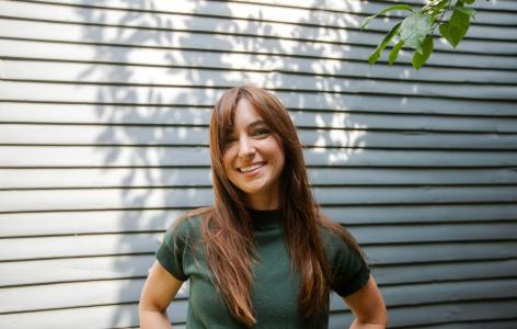 A photograph of Marissa Scavuzzo outside standing in front of siding on a house.