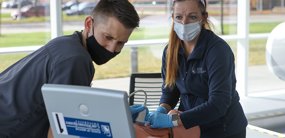 Graduate nursing students performing a critical care lab on a training manikin.