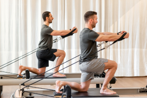 Two men on a Pilates Reformer Machine