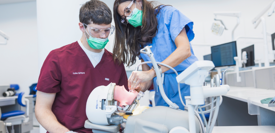 A teacher instructs a dental student.