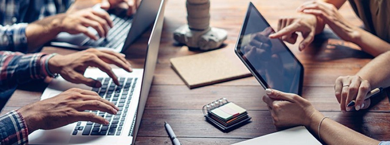People working together at a table on laptop computers