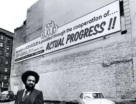 Winston Willis stands in front of a giant sign on the side of his building at E 105th and Euclid