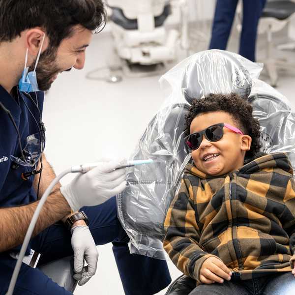 A dental student providing care to a smiling child.
