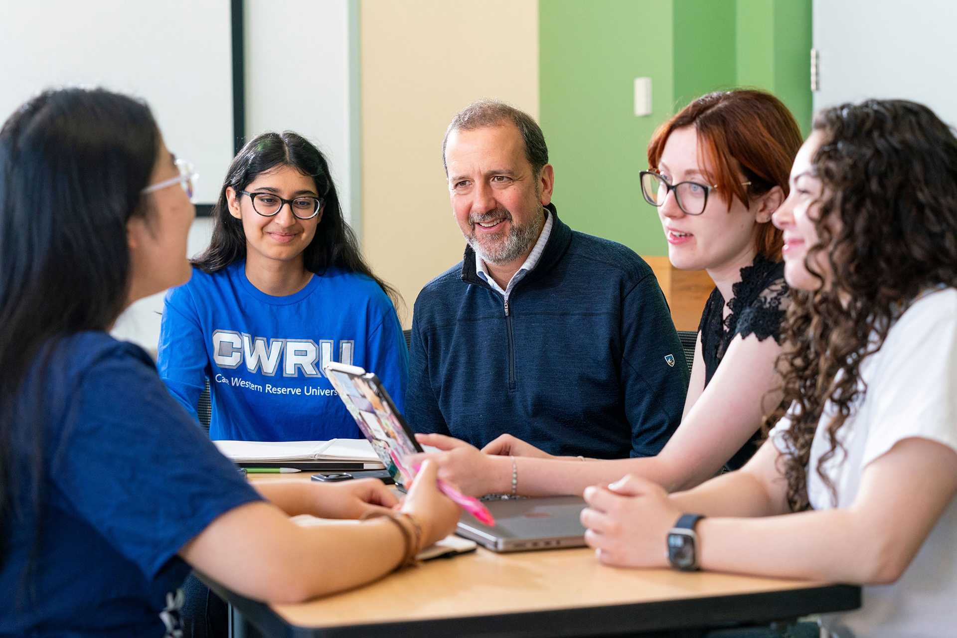 Group of students sitting at a desk talking with a teacher