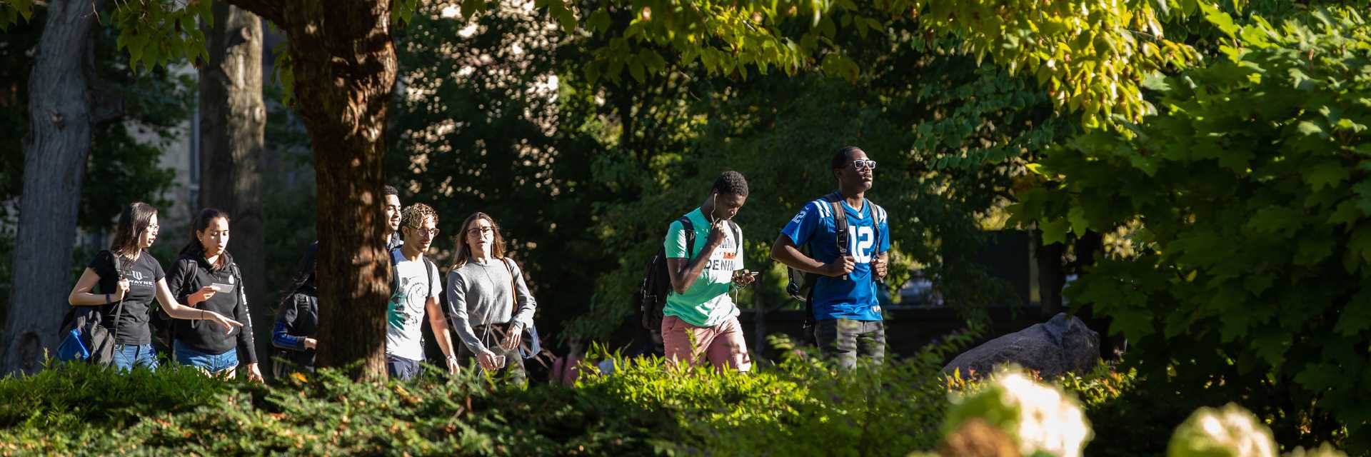 Photo of Case Western Reserve University students walking outdoors with trees surrounding