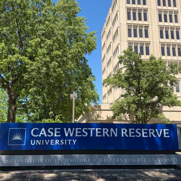 A blue and grey sign reading "Case Western Reserve University" above "Case Institute of Technology • Western Reserve University," with trees and Crawford Hall in the background.