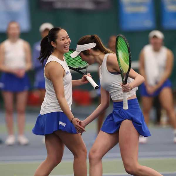 Two members of the CWRU women’s tennis team high five.