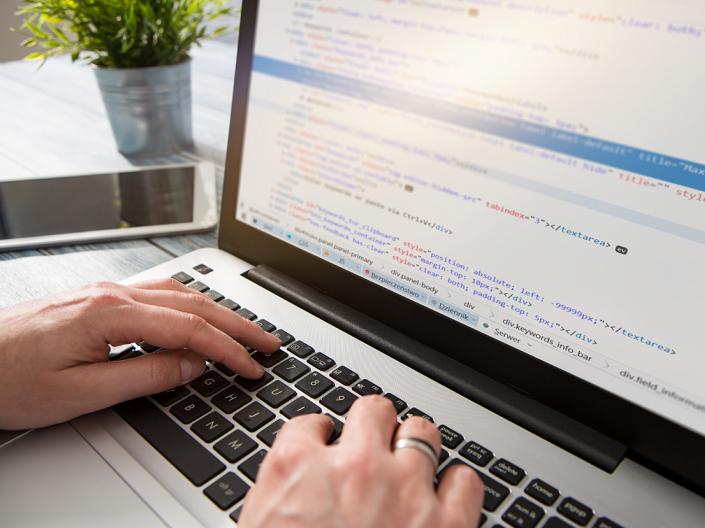 Close-up shot of hands typing on a laptop keyboard, working in a plain text editor.