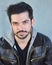 Paul Bugallo sits for camera while wearing a hooded leather jacket