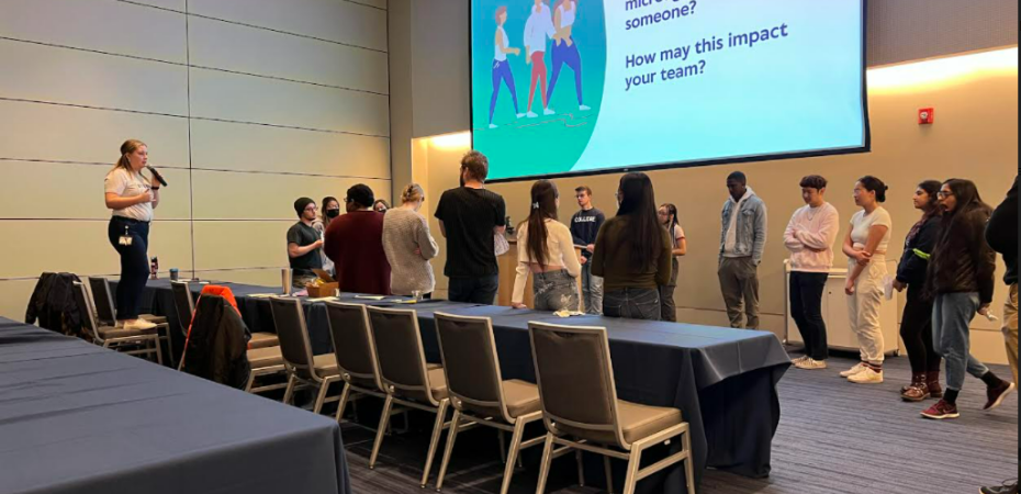 Woman standing on a chair speaking to a group of undergraduate students