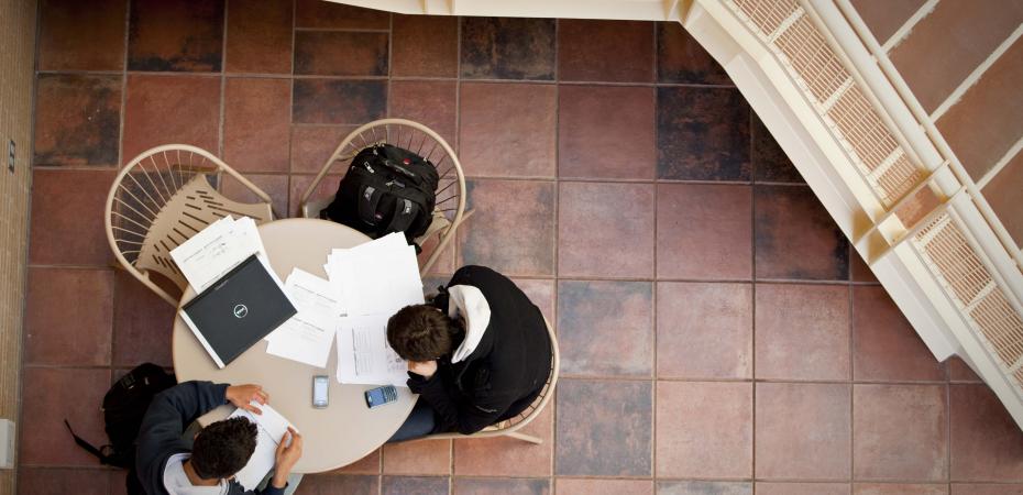 looking down on two students studying at a round table with a staircase off to the side