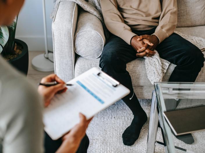 A patient sitting across from a therapist who is taking notes