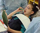 Girl brushing her teeth in dental office