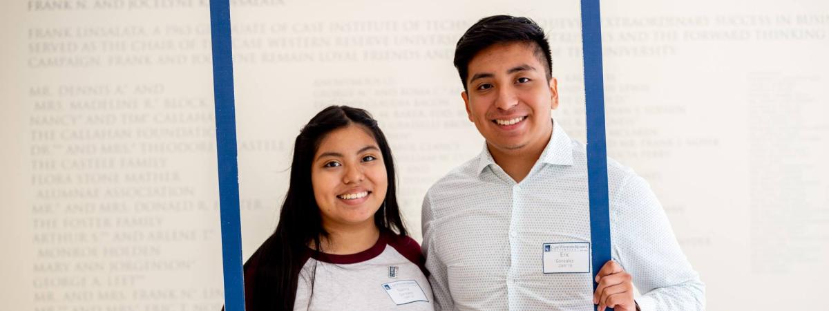 Two students holding a large frame that has the #CWRUAlumni hashtag
