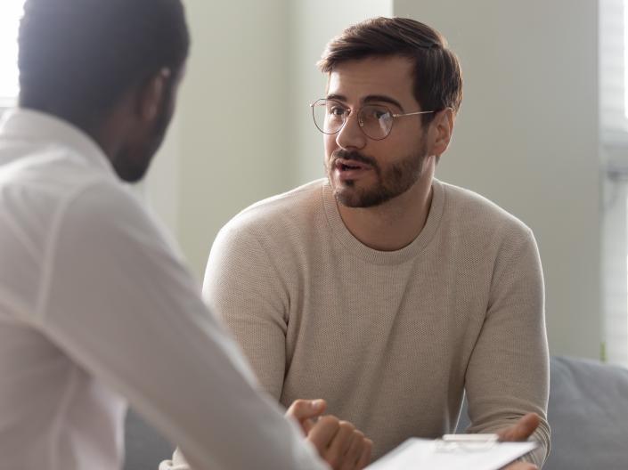 Two adults talking about a paper on a clipboard