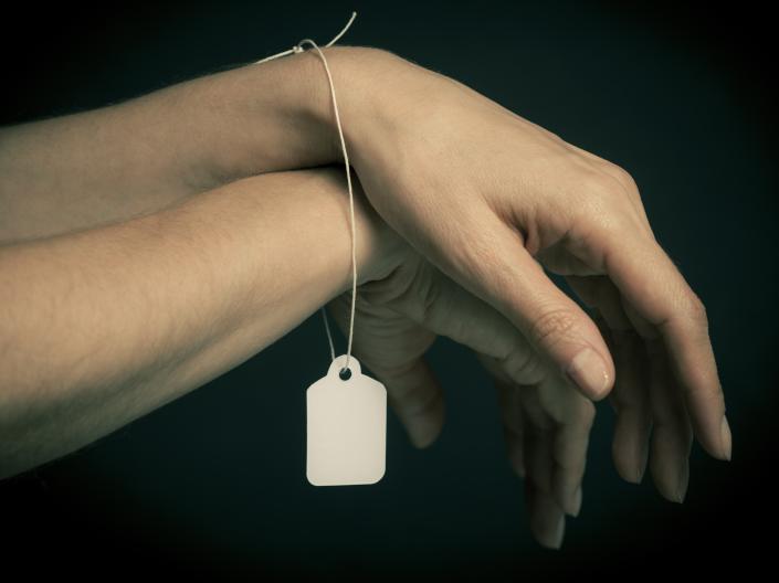 Hands crossed over each other and bound with a price tag.
