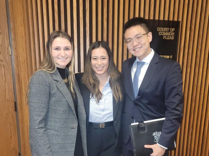 Three professionals in business attire smiling for a group photo.