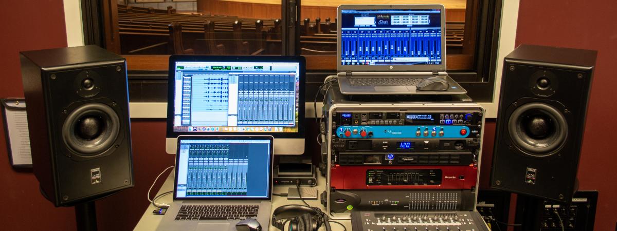 photo of three computers running ProTools and two monitors next to the desk with the computers