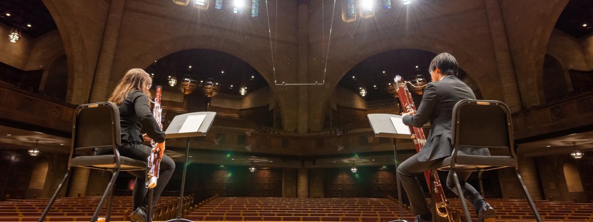 two people, both playing oboes, perform on the maltz center stage
