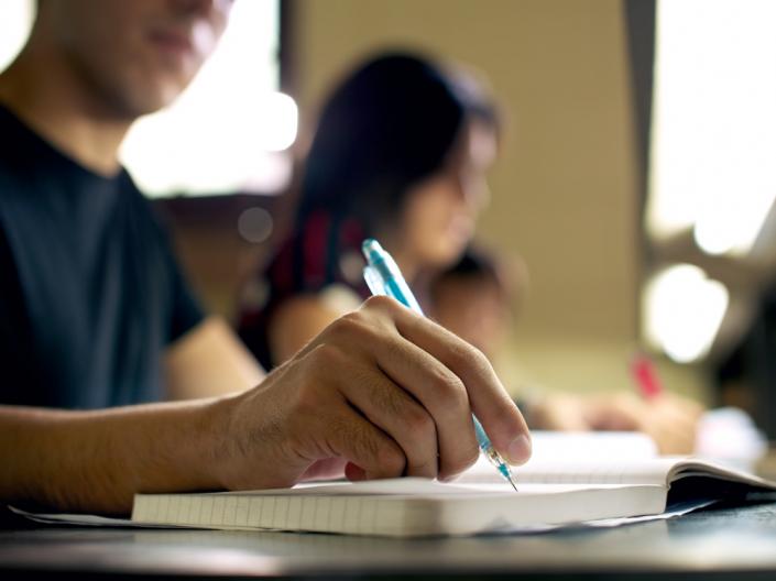 Hands writing in a notebook.