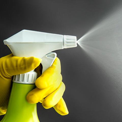 stock image of gloved depressing spray nozzle on plastic bottle