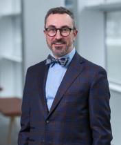 smiling man with glasses, bowtie, and dark suit