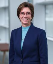 smiling woman with glasses and dark suit